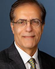Man with dark grey hair, light colored glasses and a blue plaid suit.