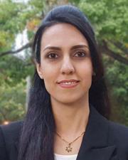 Woman with long dark hair wearing a white shirt with a black blazer.